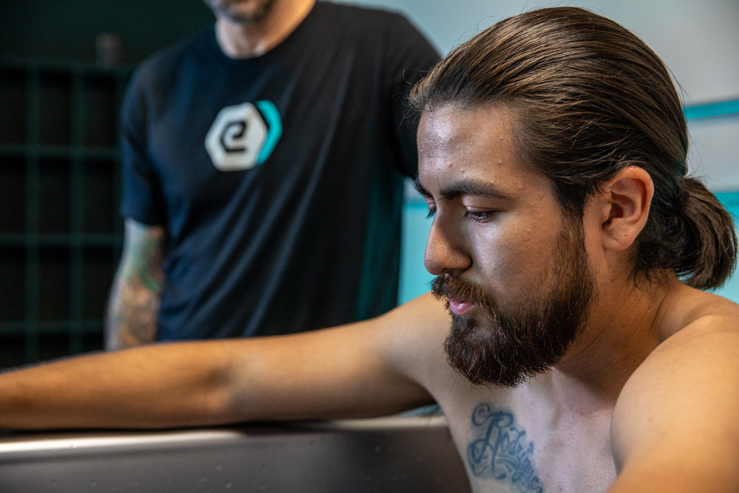 A client in the cold plunge with a coach alongside at e-motion wellness®